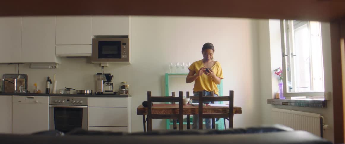 A woman using a smartphone in a kitchen