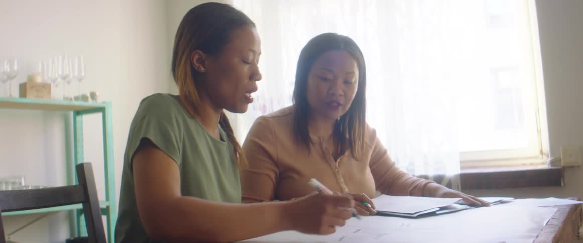 Two teenage girls work on school work together