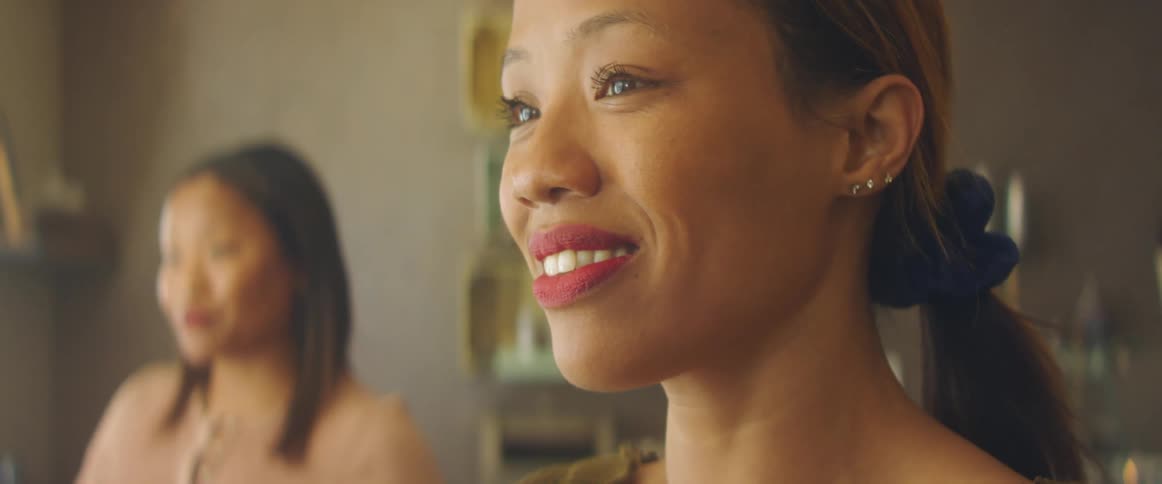 Two women are talking indoors and smiling