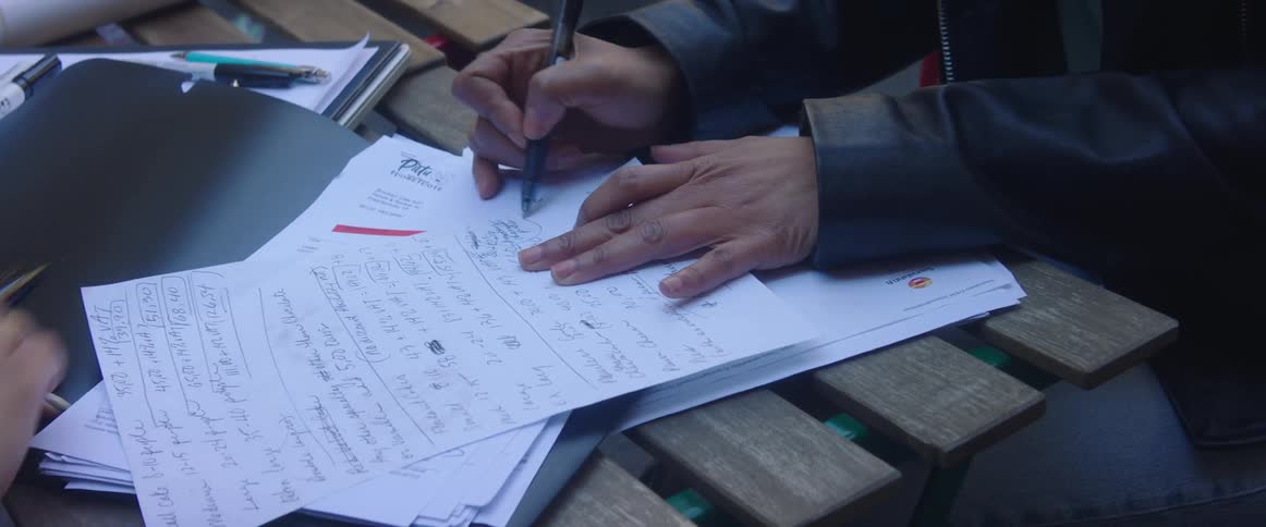 A student writes on a paper and a teacher points something out to him