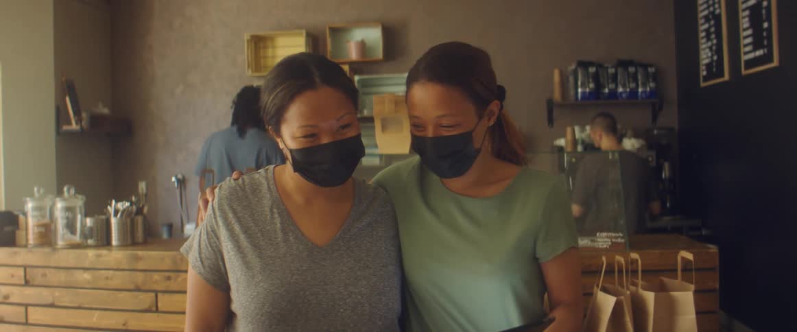 Workers wearing black face masks prepare orders to go inside a shop