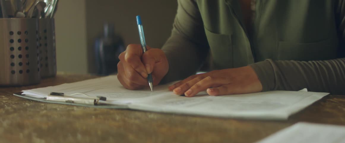 Woman with a green shirt writes in papers in the cafe shop
