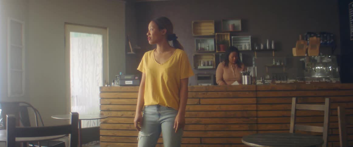 Two women stand in a store and turn to each looking confused