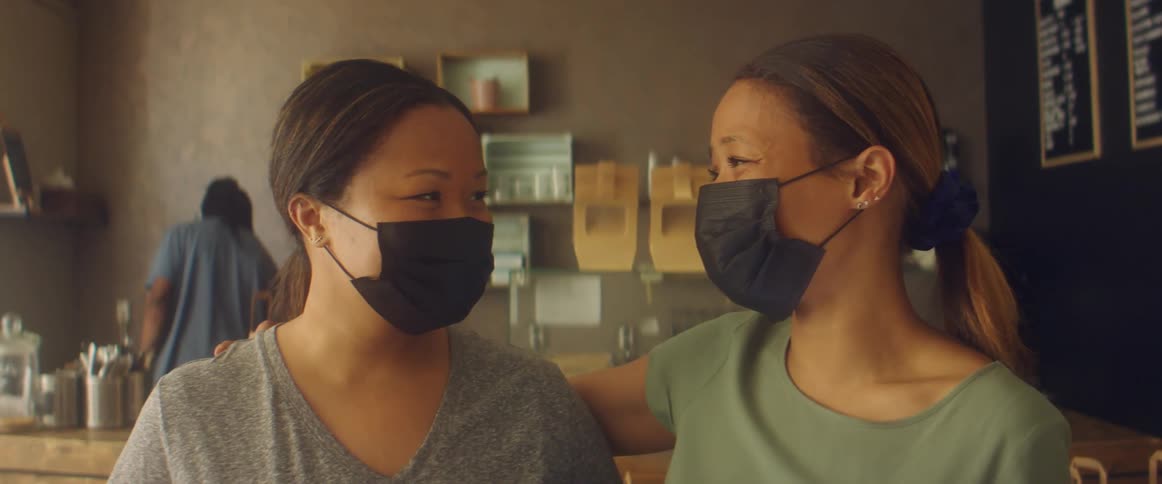 Two friends are hugging and wearing mask in a restaurant