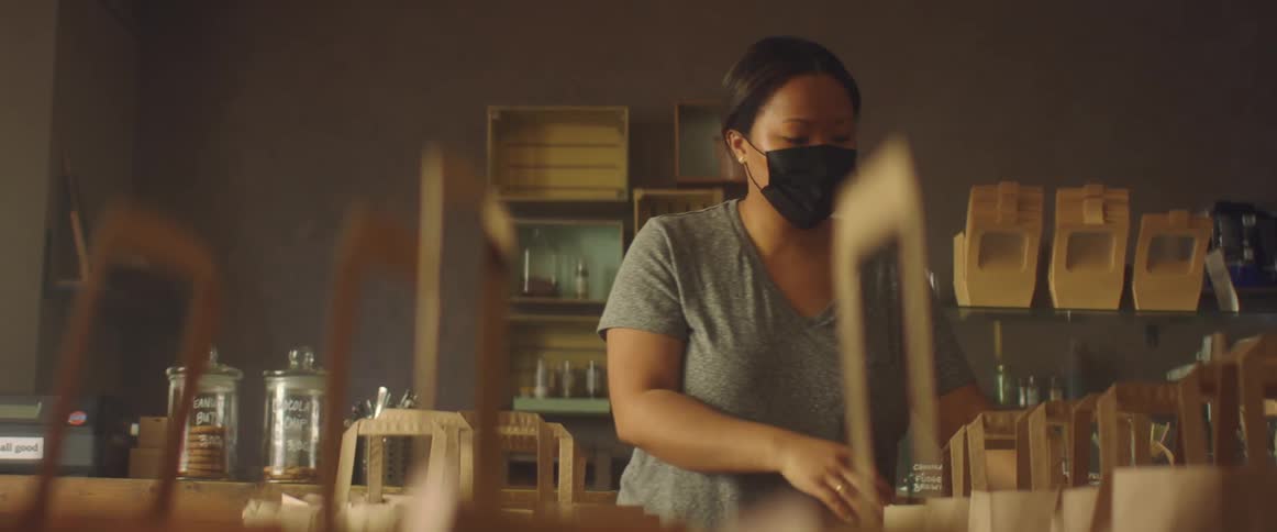 Woman wearing black face masks working on a shop preparing an order