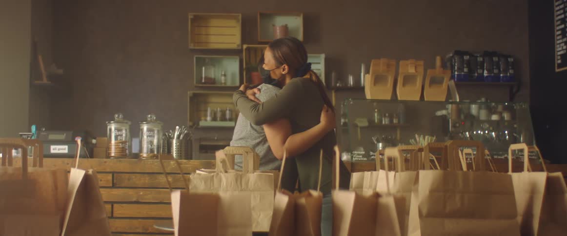 Two friends are standing in a store and hugging