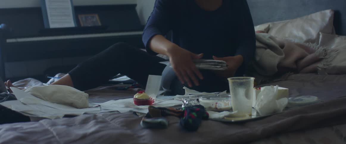 A woman is working from home going through papers on her bed
