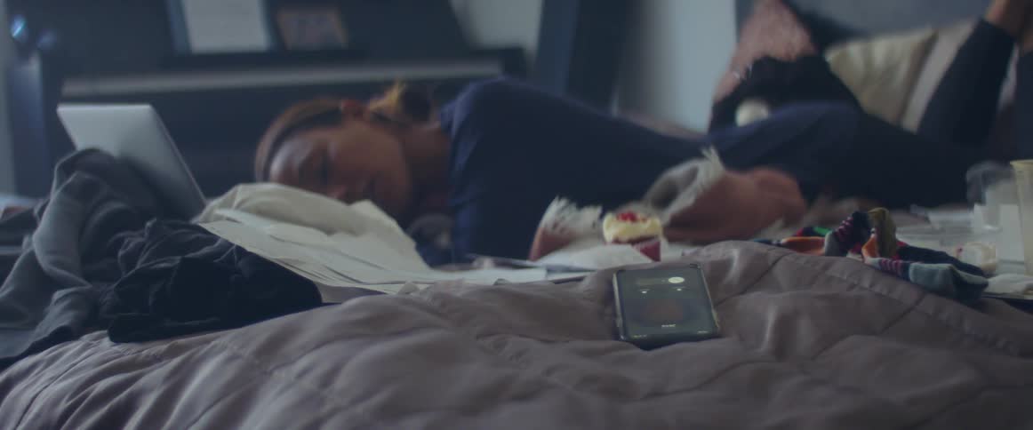 A woman taking a nap next to a smartphone