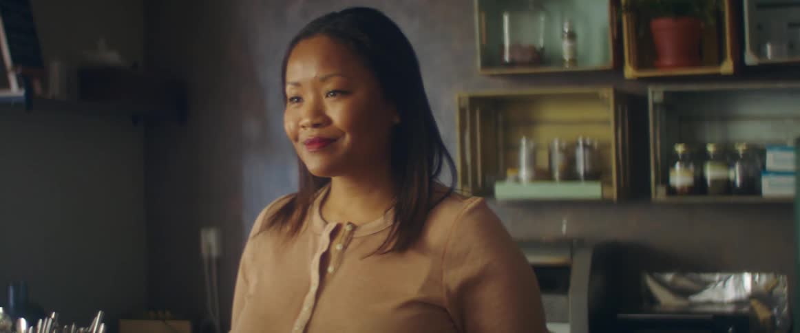 A woman is standing indoors and smiling