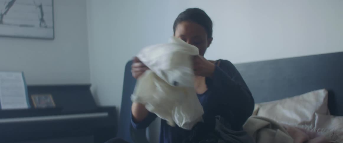 A woman is sitting on a bed and folding laundry