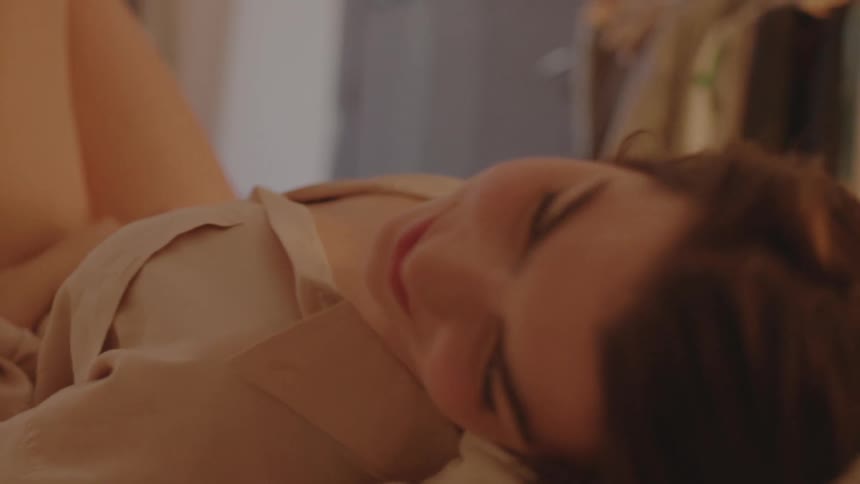 A young woman smiles as she lays on her back and relaxes while indoors