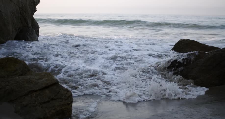 Rapidly moving water coming ashore on a rocky beach area