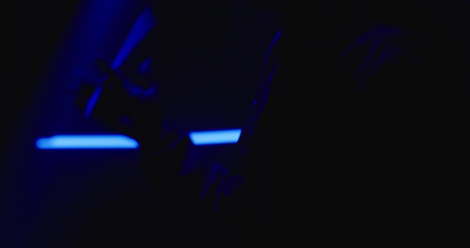 A man is wearing a hat and standing in a room with flashing lights
