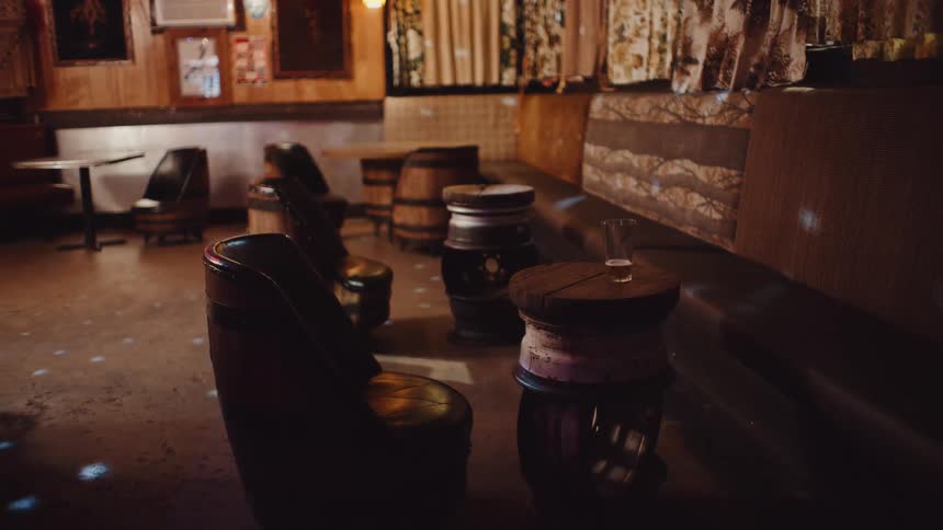 A bar with chairs and tables with a wall and curtains in the background