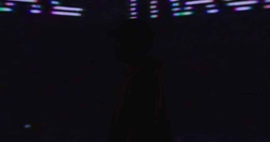 Man stands in dark night club near wall sized screens showing changing images