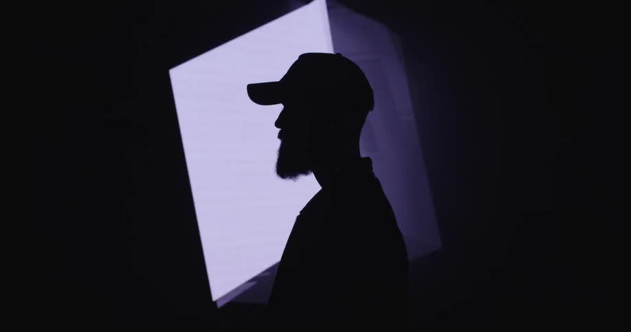 A silhouetted man standing in front of a rotating digital cube
