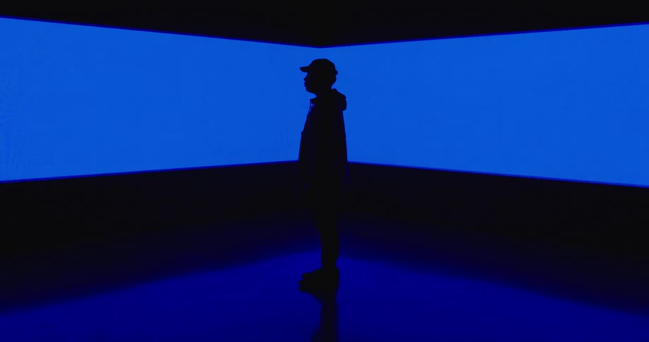 A silhouetted man in front of blue projections on a wall