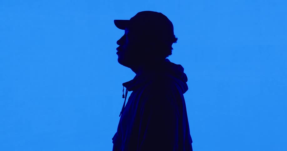 The silhouette of a man can be seen as he stands in front of a large screen with a bright color displayed