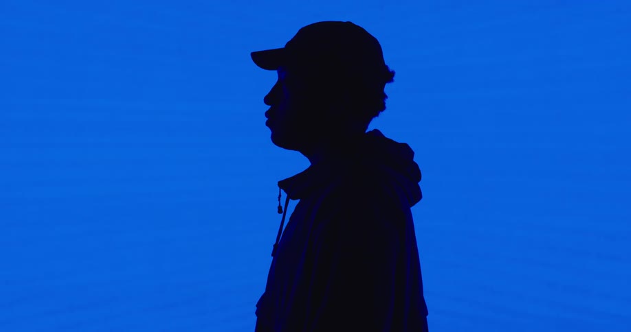A man stands in front of a blue screen