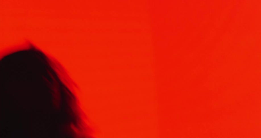Woman moves through club changing between bright colors and darkness