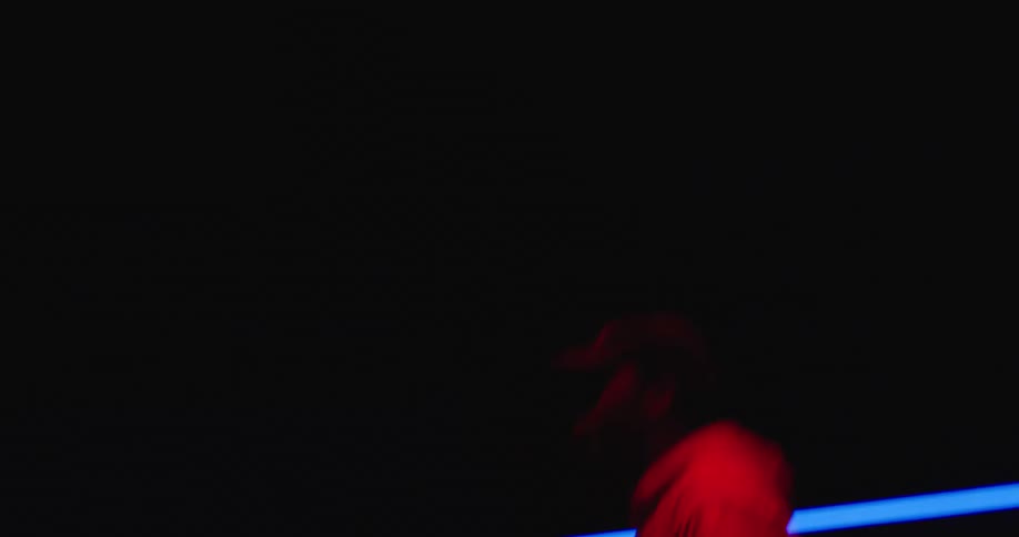 A man is spinning his drumsticks in the dark room