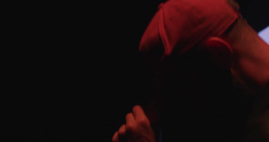 A man adjusts his hat on a stage