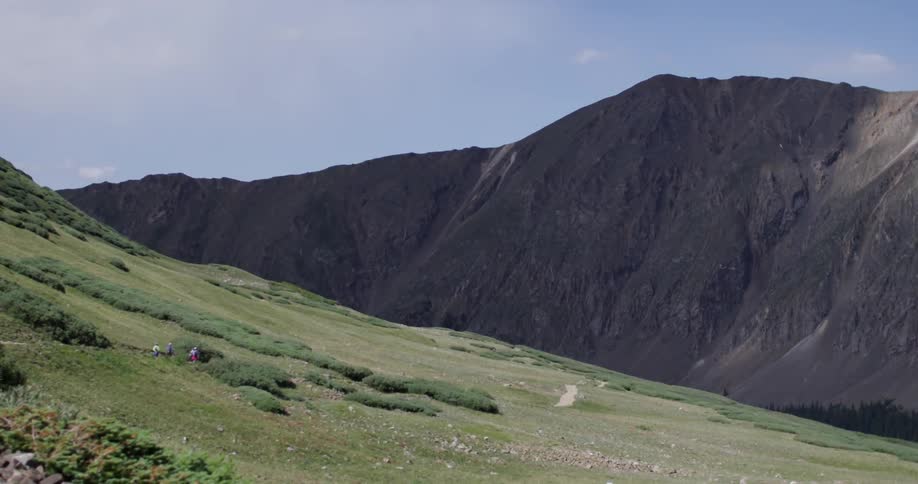 Grassy hillside with a dark mountain in the background on a clear day