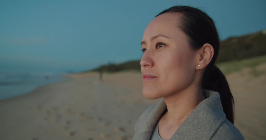 A woman standing alone on a sandy beach
