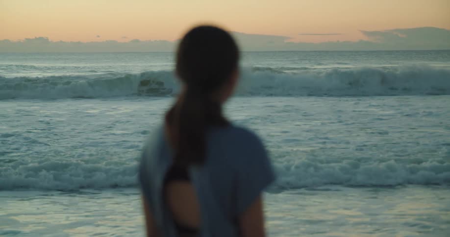 A woman standing at the ocean staring
