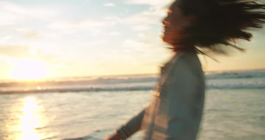 Happy woman jumping and spinning in front of the ocean at sunset