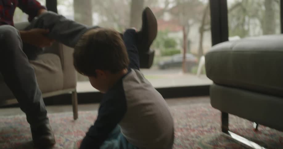A father is sitting in a chair and playing with his son