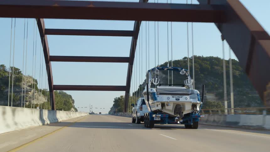 A truck pulls a boat along a bridge