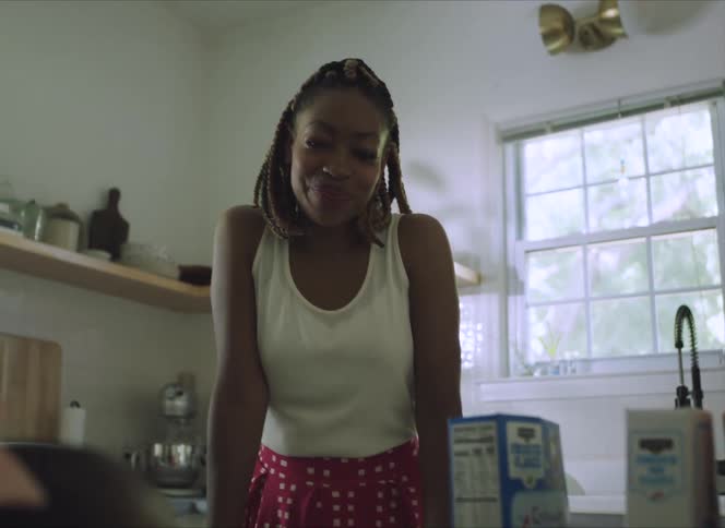 A mother smiles as she watches her young daughter pick a box of cereal to eat