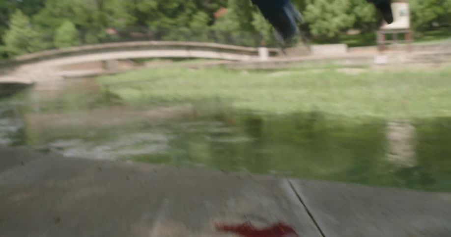 A person jumps into the river with their cap and gown on