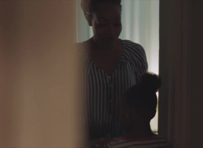 A woman walking to her young daughter in a hallway at home