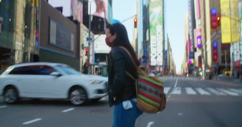 Woman wearing a face mask crosses the street on the citys downtown