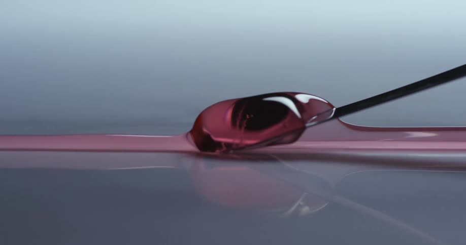 Purple liquid is being moved across a surface