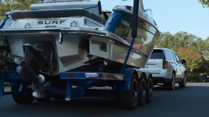 White vehicle tows a boat down the neighborhood street