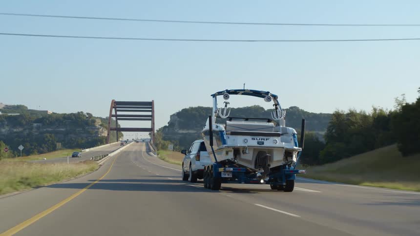 Car towing a boat on the highway about to cross a bridge at morning