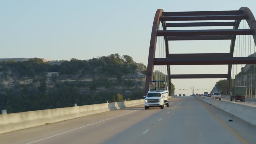 An suv pulls a boat across a large bridge
