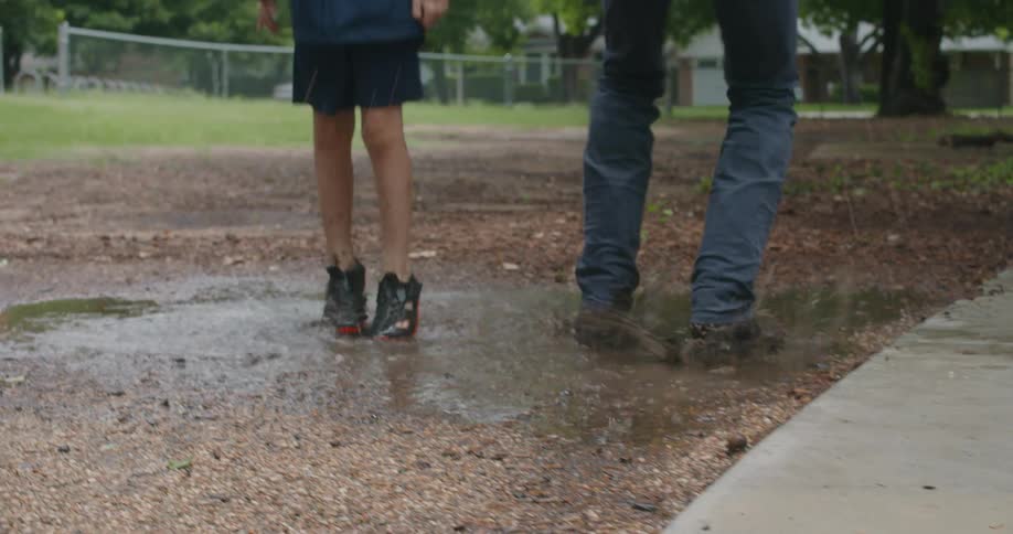 A father and son are jumping in puddles of water