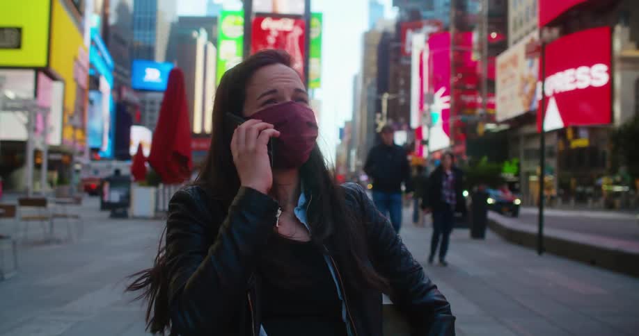 Woman wearing a face mask answers a phone call in the city dowtown