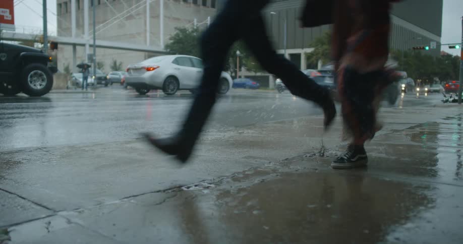 Couple running together on the wet sidewalk on a rainy day