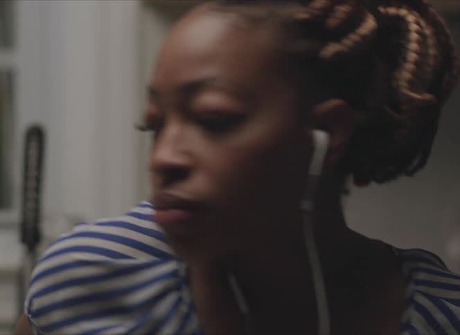 A woman is putting on earphones and then turning away