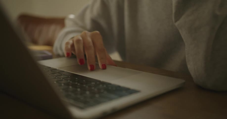 A woman sits at a table concentrating on a laptop