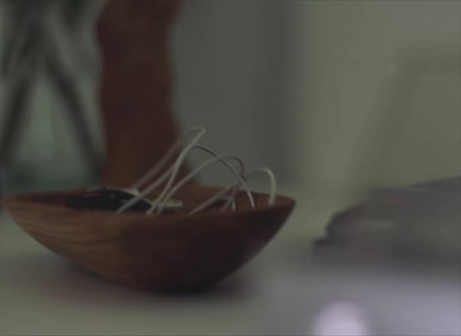 Person wearing pink nail polish drops keys in wooden bowl