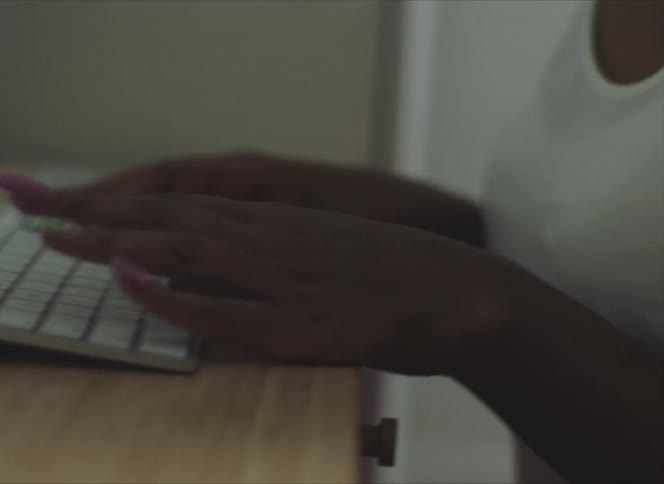 Close up of a womans hands as she types on a computer keyboard in an office