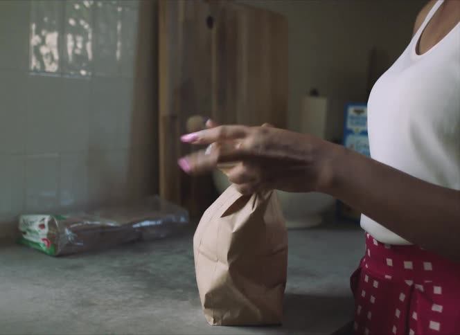 Woman packing school lunch in a bag in the kitchen at home