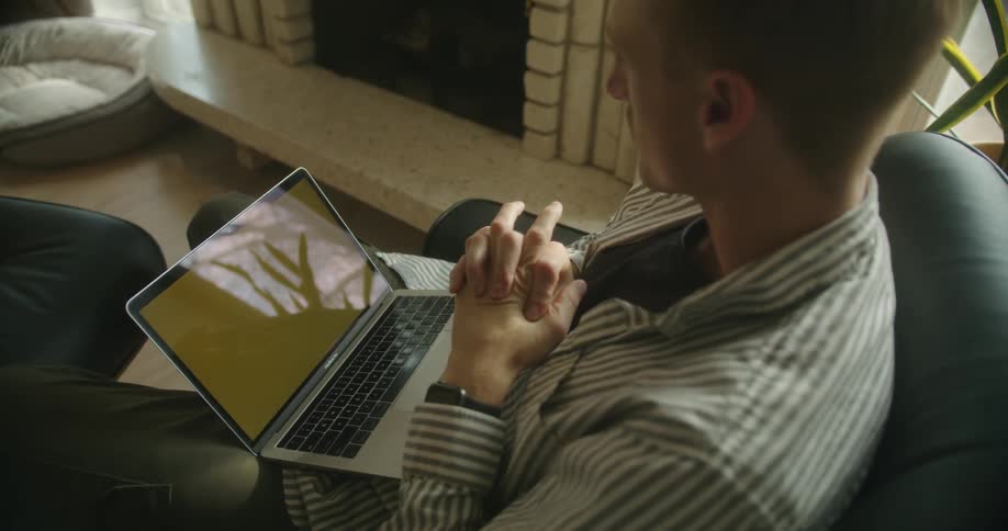 Man sitting in a chari on the living room talking in front of a laptop with a replaceable screen