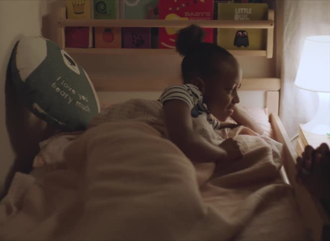 Mother tucking her daugther on the bed at night
